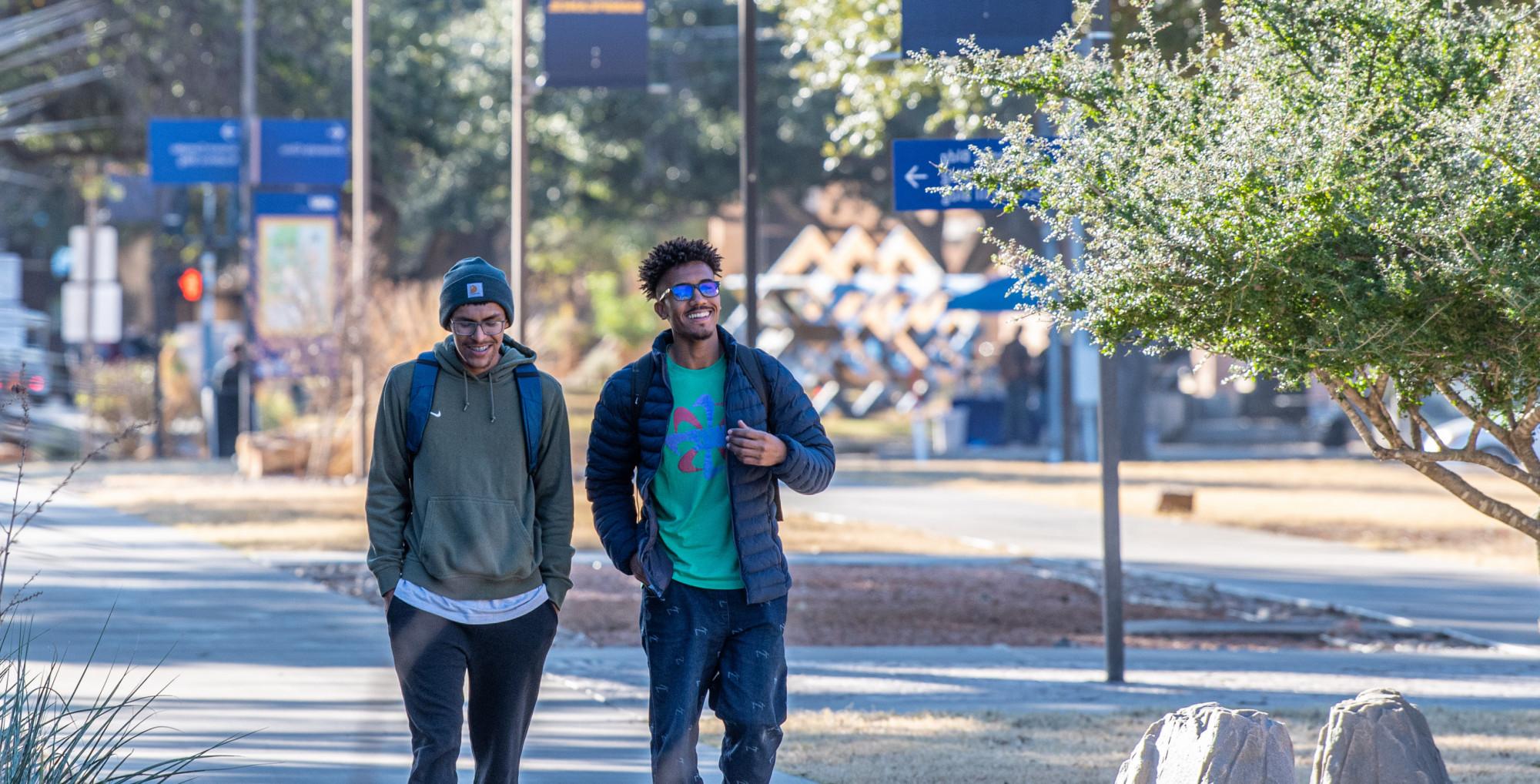 两个学生走在长长的人行道上聊天.